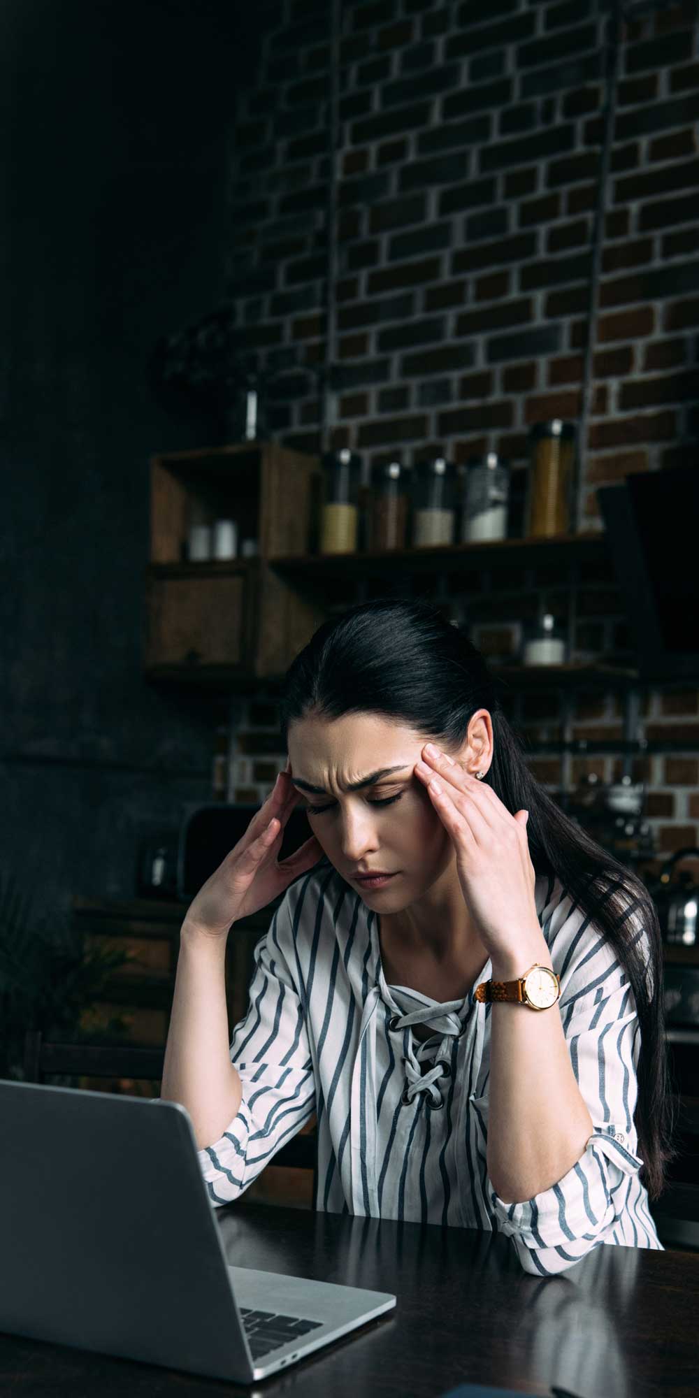 A business owner at her laptop with her head in her hands, worn out by the twenty steps beside her.